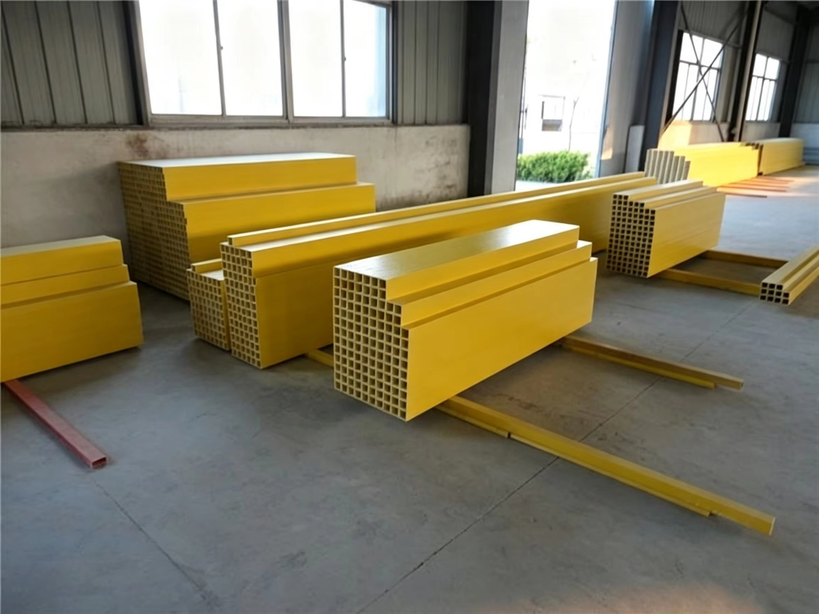 Yellow profiles stacked in the warehouse and workshop area under natural light from large windows