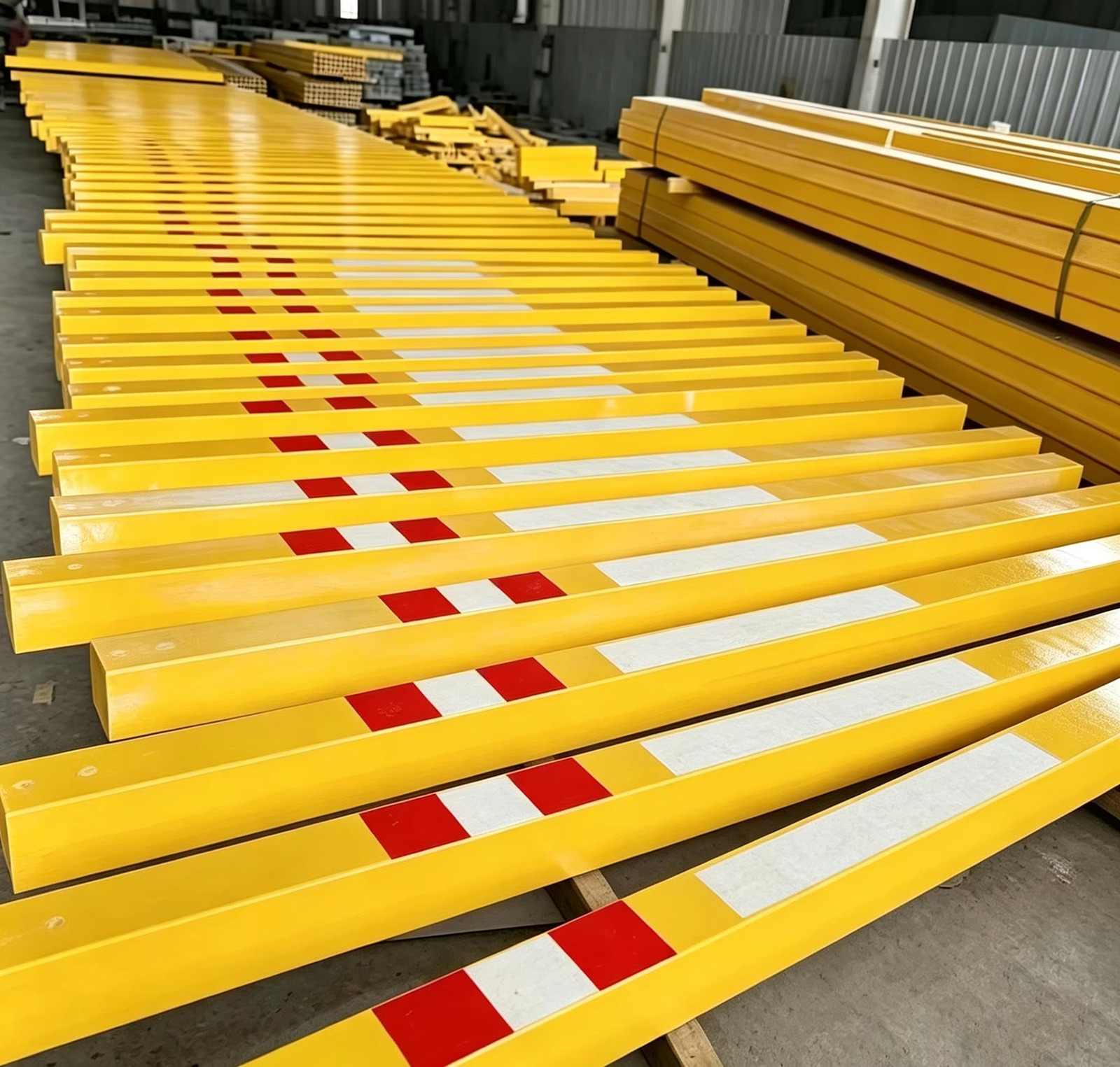 Steel and FRP profiles staged in rows inside the workshop